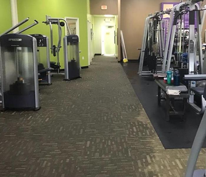 gym with standing water on gray carpet 