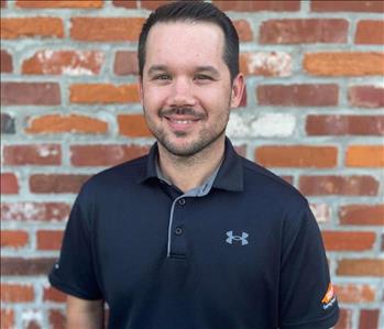 man in blue polo shirt with SERVPRO logo standing in front of brick wall