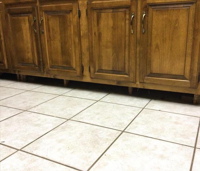 brown kitchen cabinets with toe kicks removed and white flooring tile